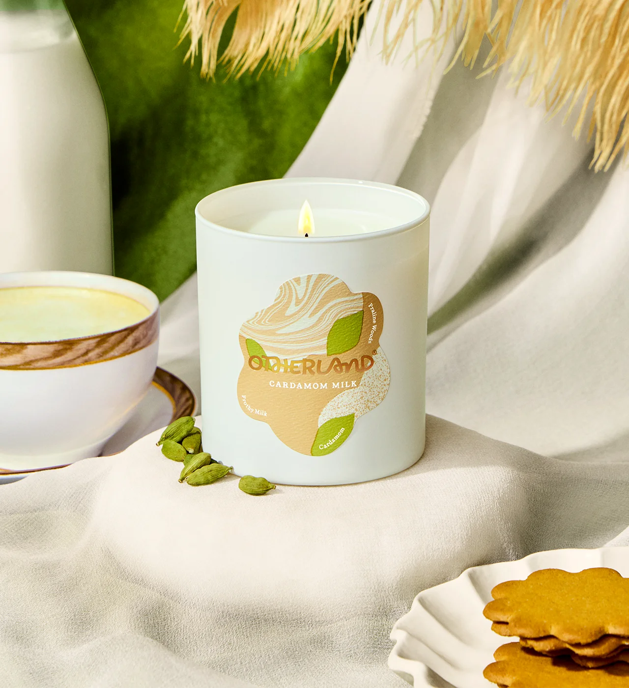 Candle with a Otherland logo on a table with cookies and greenery - View 2