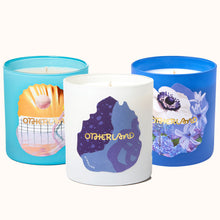 Three candles with colorful designs and 'Otherland' branding on a white background