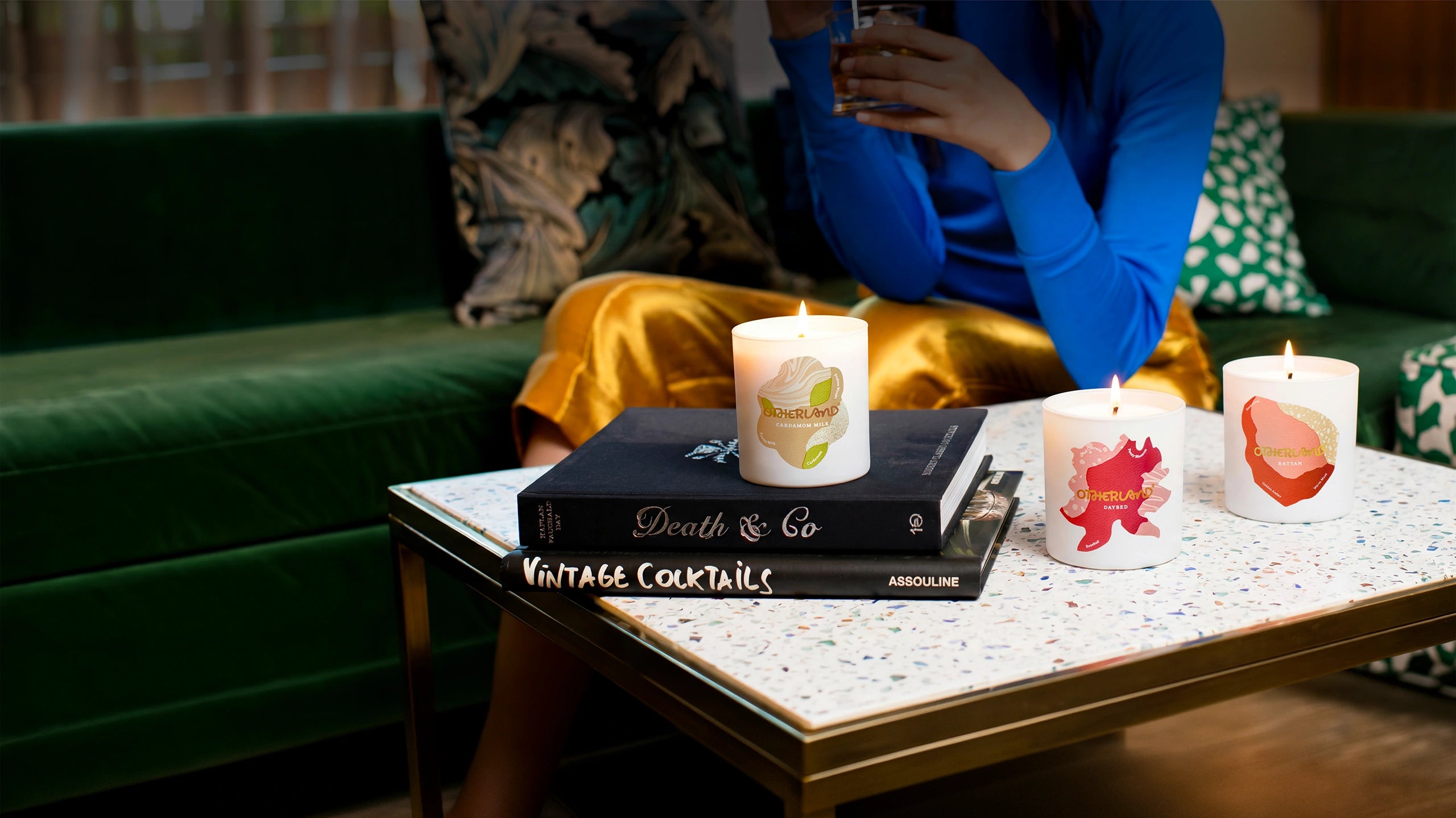 Candles on books with a person sitting on a couch in the background