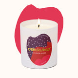 Candle with 'Otherland' branding in front of a pink lip-shaped object