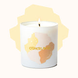 Candle in a container with 'Otherland' branding on a white background