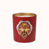 Red candle with gold lid and decorative label on a white background