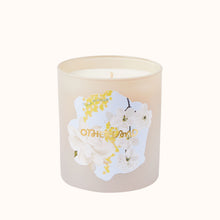 Candle with floral design and 'Otherworld' branding on a white background