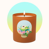 Candle in a terracotta container with a decorative label on a white background