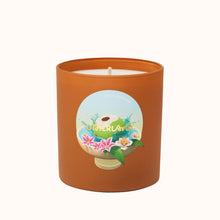 Candle in an orange container with a decorative label on a white background