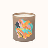 Candle with colorful design on a beige container against a white background