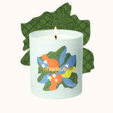 Candle with colorful leaf design and 'Otherland' branding on a white background
