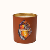 Candle in a brown container with a gold lid on a white background