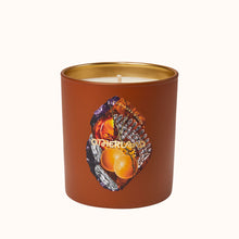 Candle in a brown container with a gold lid on a white background