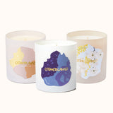 Three candles with colorful labels and 'Otherland' branding on a white background