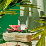Otherland Organic Canopy tea package with figs on a stone surface surrounded by green leaves.