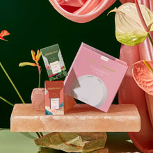 Pura diffuser kit on a pink stone surface with flowers and fabric in the background