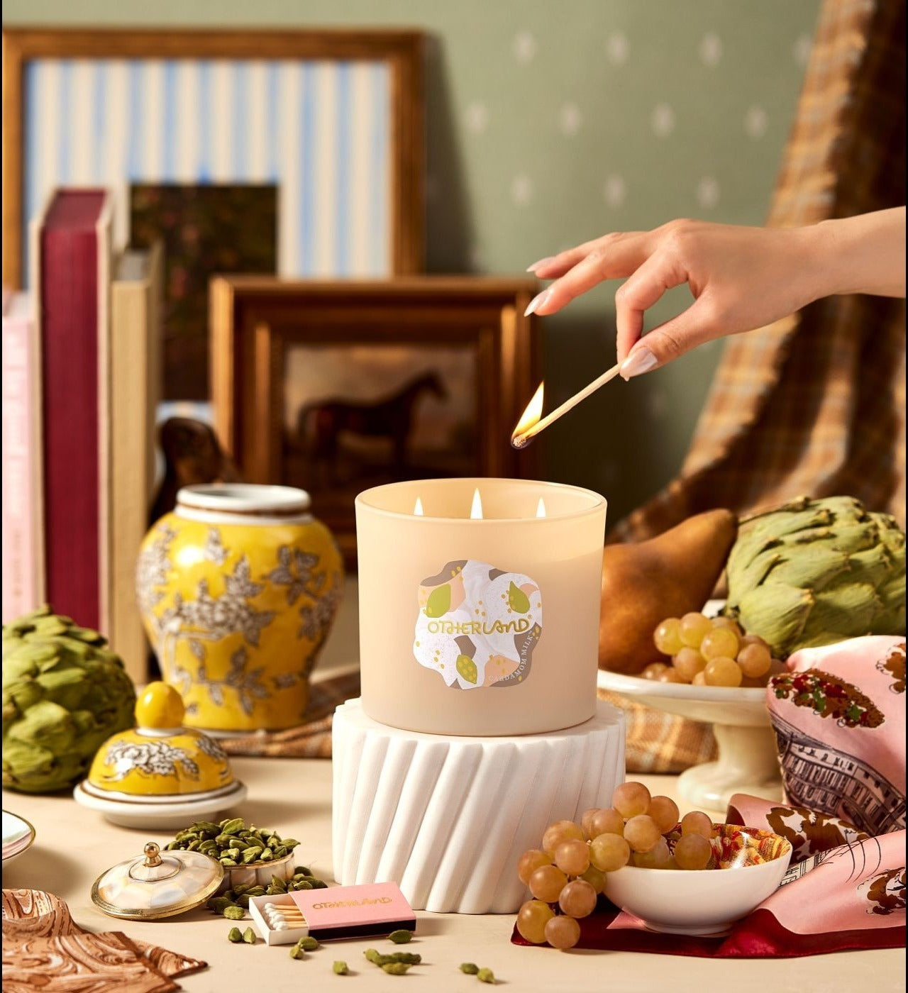Hand lighting a candle with decorative items around - View 2