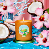 Candle with a floral label on a blue surface with pink flowers and coconuts.
