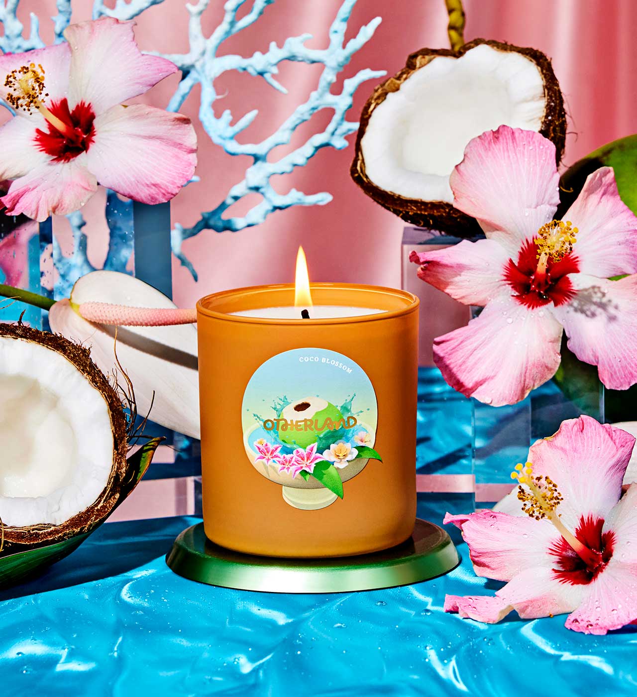 Candle with a floral label on a blue surface with pink flowers and coconuts. - View 2