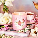 Pink candle with floral design on a table with flowers and a teacup.