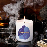 Candle with 'Otherland' logo on a dark background with smoke and rocks.