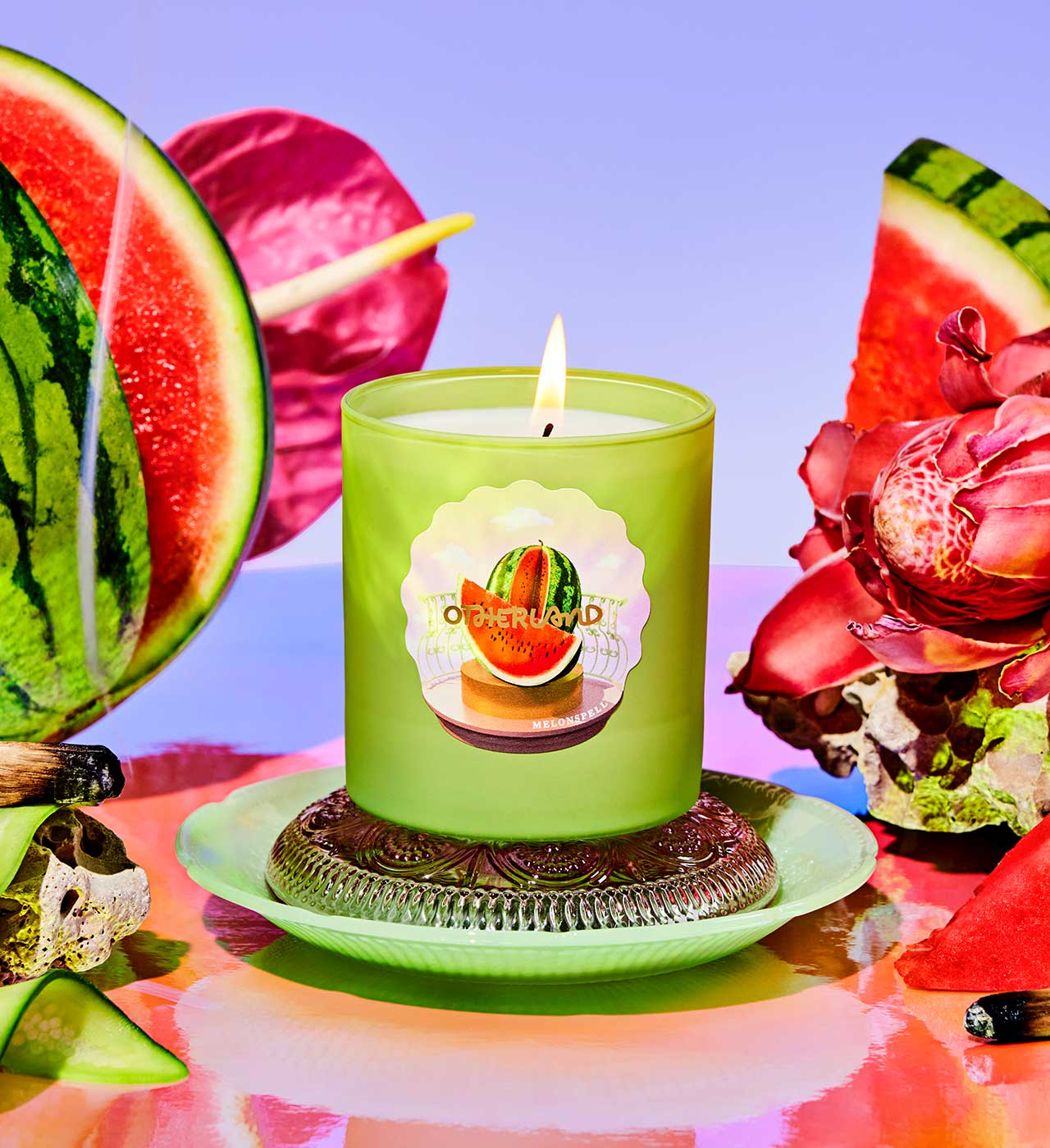 Green candle with watermelon design on a colorful background with watermelon slices and flowers. - View 2