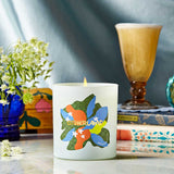 Candle with colorful design on a table with books and flowers