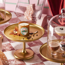 Candle on a gold tray with decorative elements on a checkered tablecloth