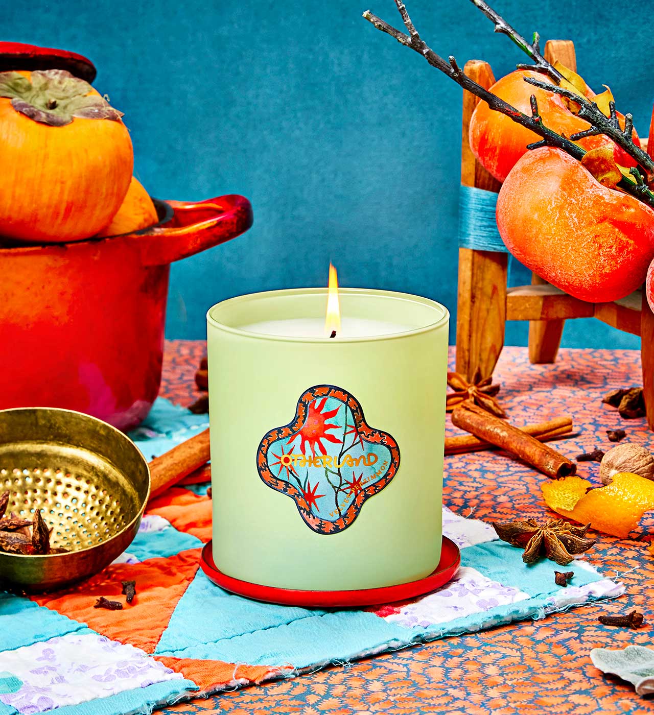 Candle with decorative label on a colorful tablecloth with pumpkins and cinnamon sticks. - View 2